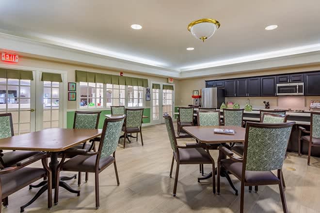 A cozy dining area with tables and chairs adjacent to a kitchen space.