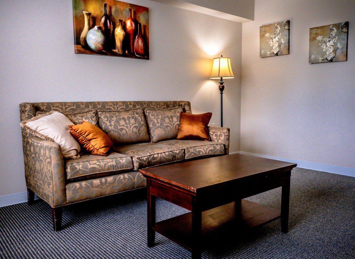 A cozy living room with a patterned sofa, wooden coffee table, and warm lighting.