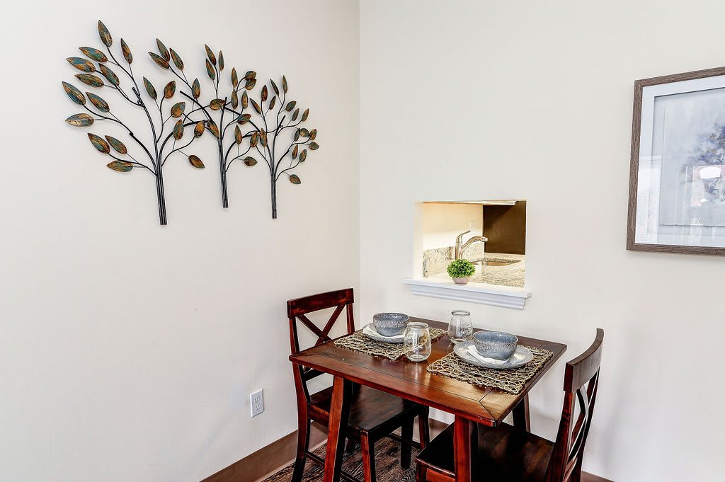 Cozy dining nook with a small wooden table, set for two, adorned with wall art.