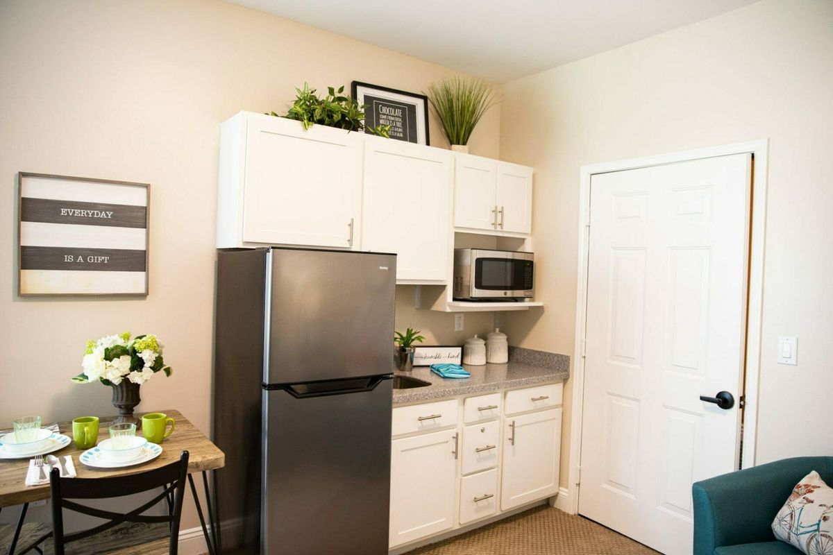 A small modern kitchen with white cabinets, a refrigerator, and a microwave.