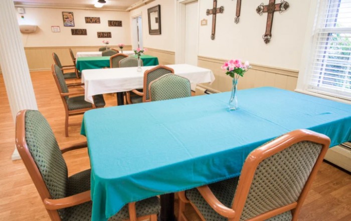 A dining area featuring tables with colorful tablecloths and floral centerpieces, adorned with cross decorations on the walls.