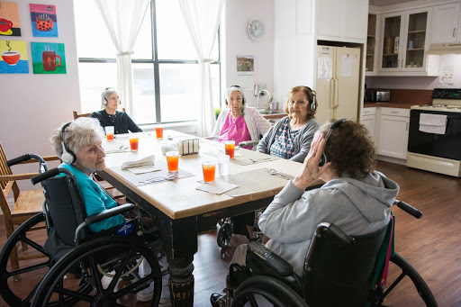 A group of elderly individuals enjoying a social gathering around a dining table in a care facility.