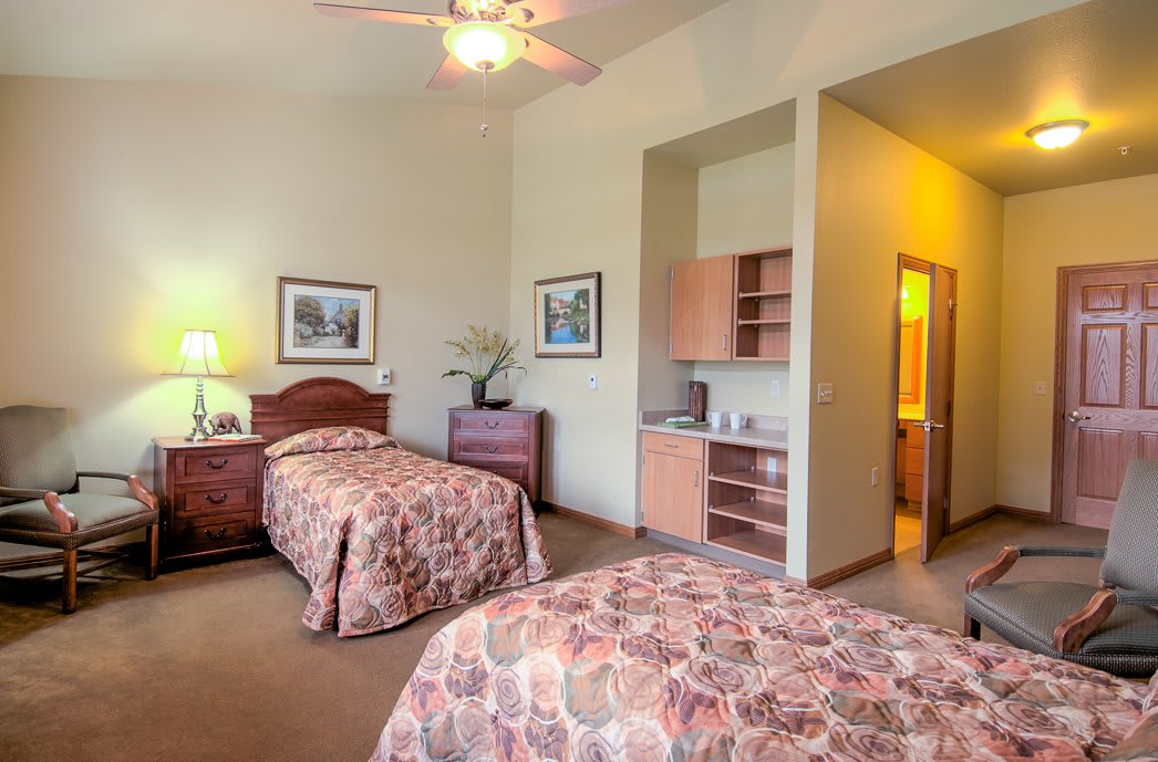 A cozy bedroom with two single beds, warm lighting, and a small kitchenette.