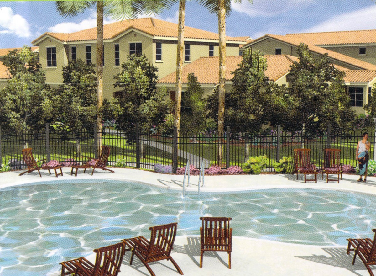A tranquil outdoor swimming pool surrounded by lounge chairs and lush greenery, set against residential buildings under a sunny sky.