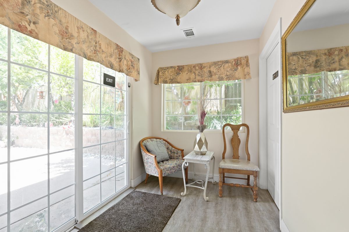 A cozy sitting area with chairs, a small table, and large windows providing natural light.