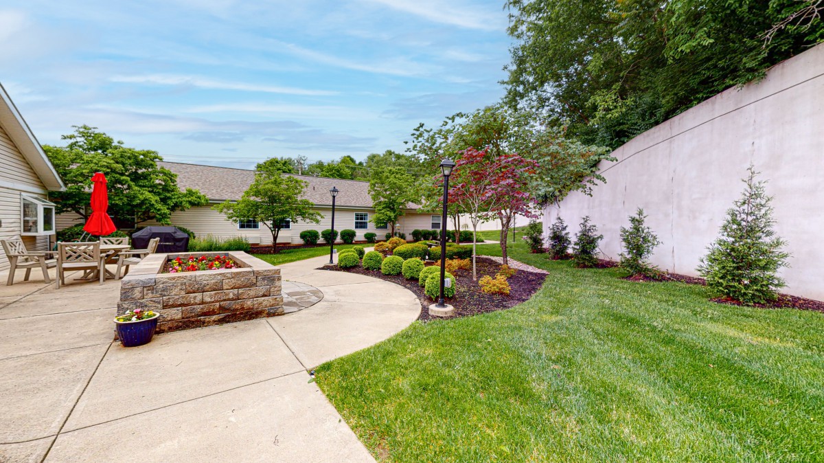 A beautifully landscaped garden with a winding pathway, surrounded by lush greenery and trees.