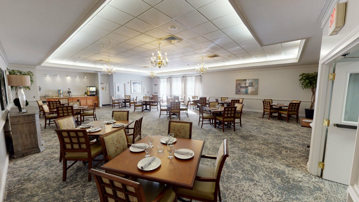 A spacious dining room with elegantly set tables and a chandelier.