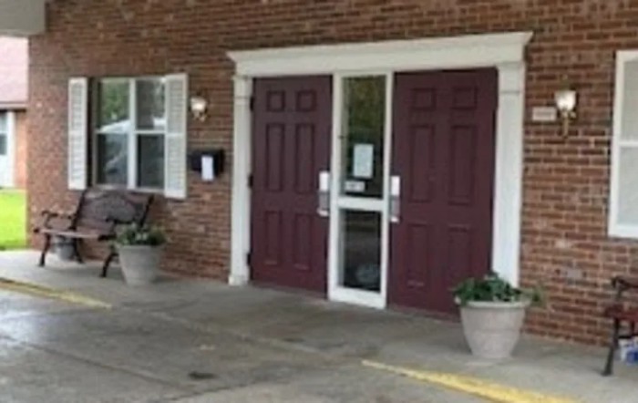 A building entrance with double doors and potted plants.