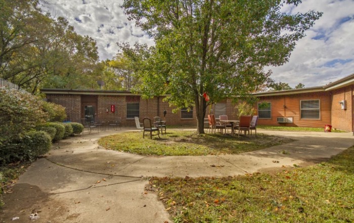 A peaceful courtyard with outdoor furniture and a tree surrounded by a building.
