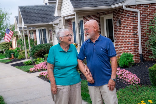 An elderly couple enjoys a moment together in their picturesque neighborhood, holding hands and sharing smiles.