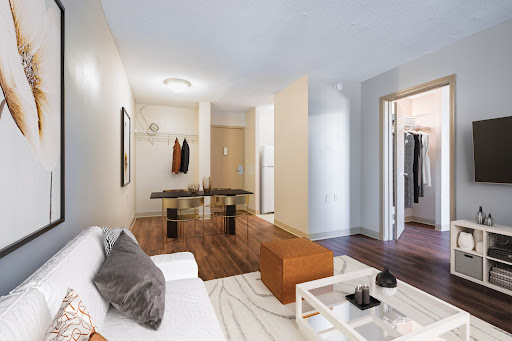 A modern living room showcasing an open layout with stylish furniture and warm wood flooring.