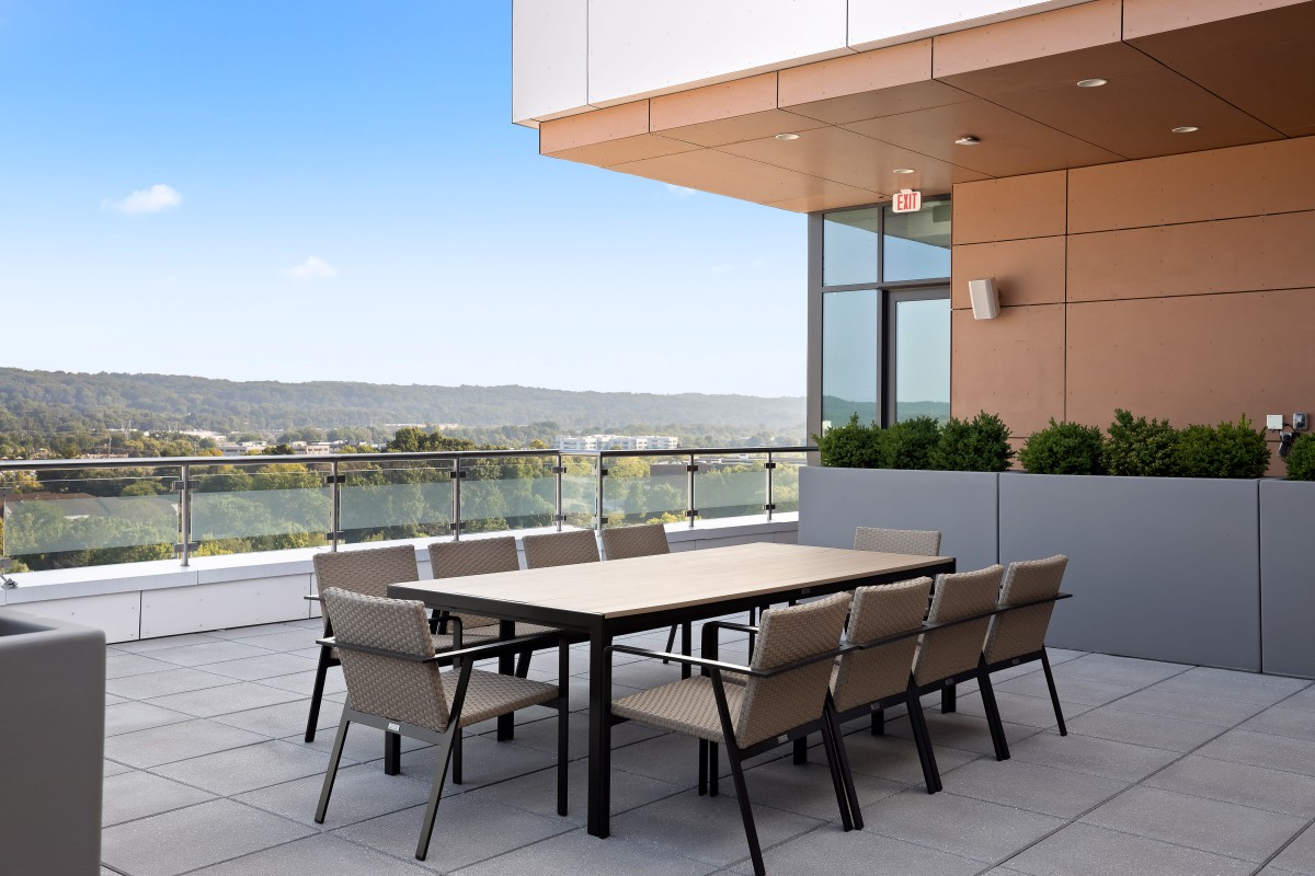 Modern patio with a table and chairs overlooking a scenic view.