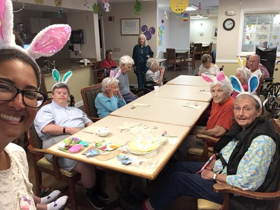 A group of seniors wearing bunny ears gather around a table for crafts and festivities.