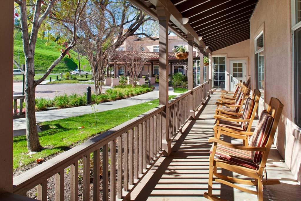 A sunny porch with wooden rocking chairs overlooking a landscaped garden.