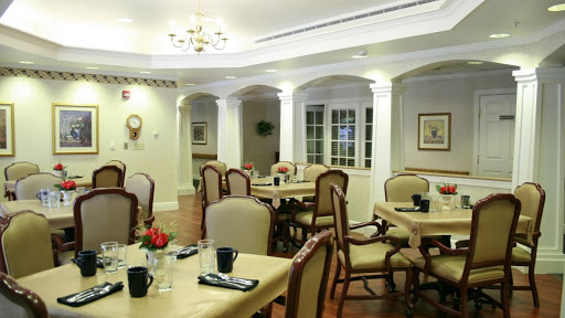 A cozy dining area featuring elegantly arranged tables and chairs, illuminated by a chandelier.