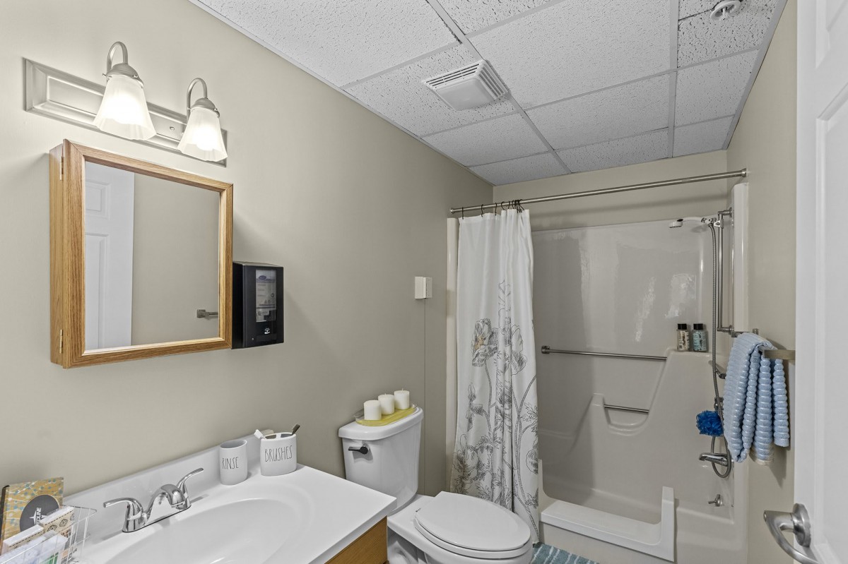 A clean, modern bathroom featuring a sink, toilet, and shower area with a curtain.