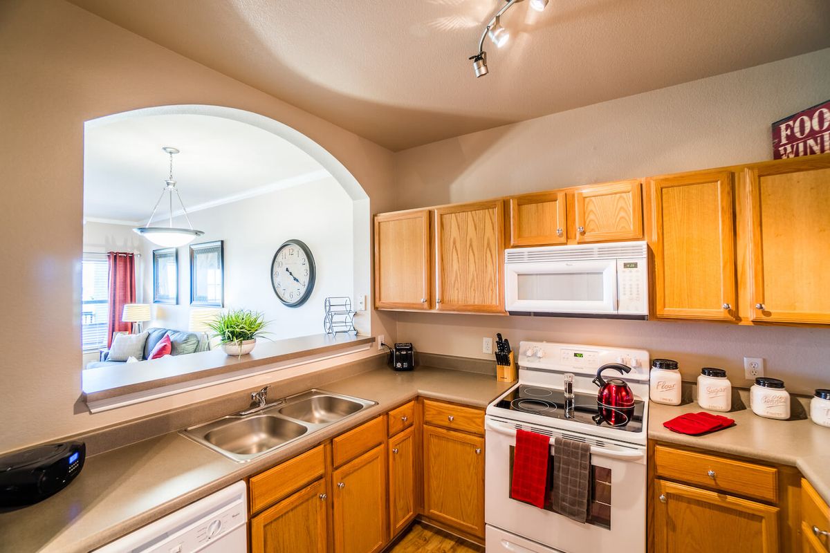 A modern kitchen with wooden cabinets, a sink, and appliances including an oven and microwave.