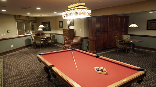 A cozy game room featuring a red felt pool table and ambient lighting.