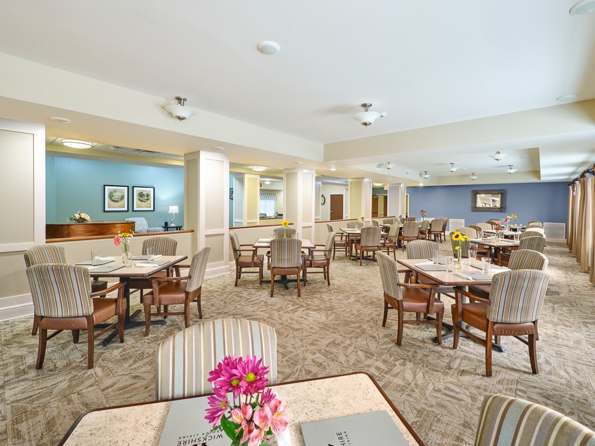 A spacious dining area with well-arranged tables and chairs, decorated with vibrant flowers.