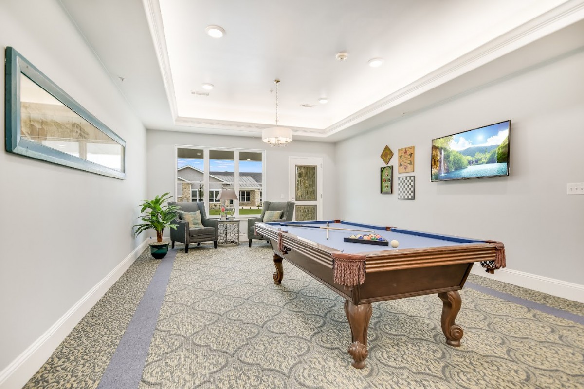 A well-lit game room featuring a billiard table, comfortable seating, and stylish decor.