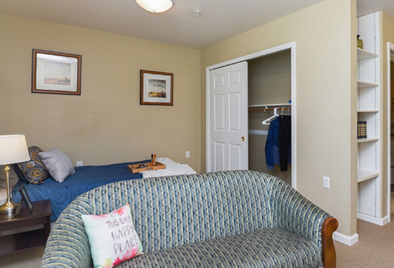 A cozy bedroom with a bed, sofa, and an open closet.