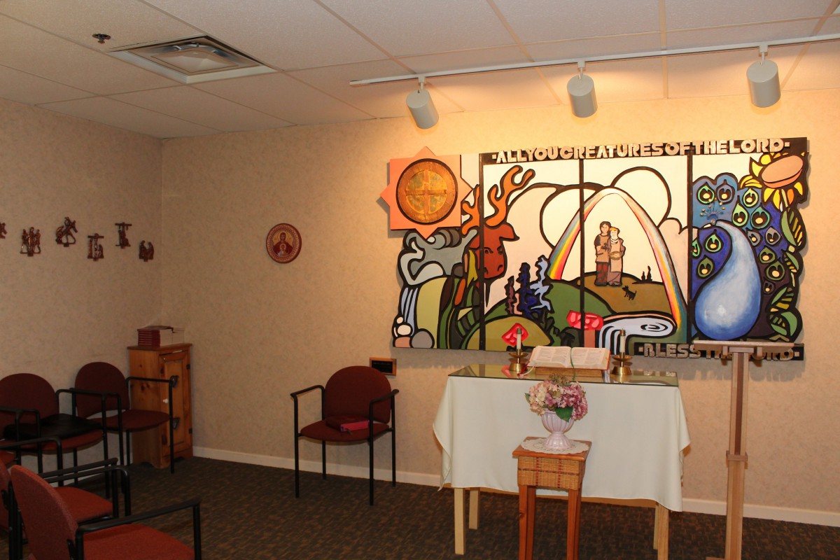 A chapel interior with a colorful painting and altar setup.