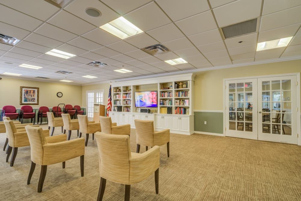 A well-lit meeting room with a television, chairs, and bookshelves.