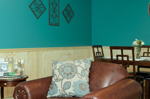 A cozy corner of a living room featuring a leather couch adorned with a decorative pillow against teal walls.