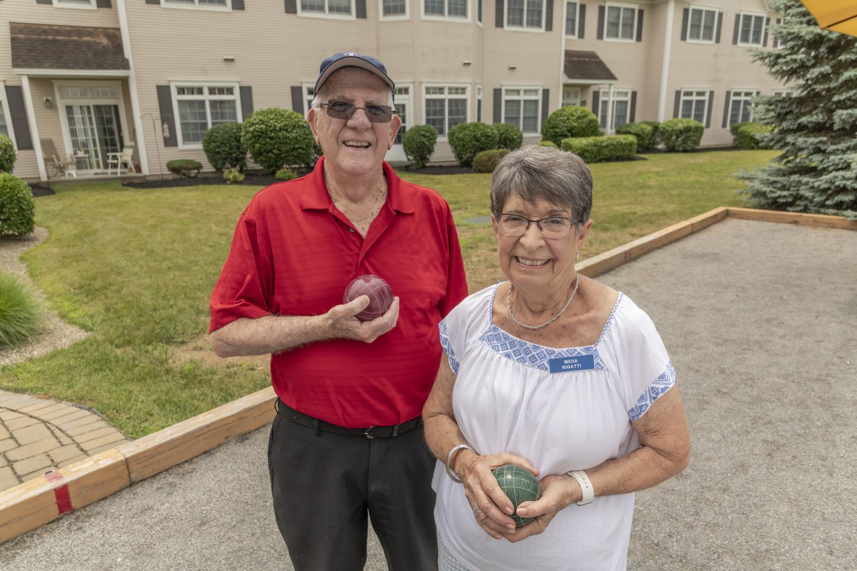 An elderly couple enjoying a game of bocce ball outdoors.