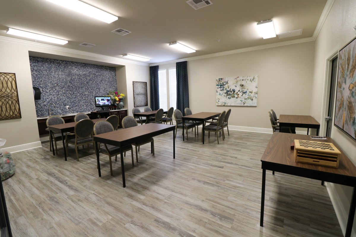 A modern classroom or meeting space with multiple tables and chairs, featuring a neutral color scheme and contemporary decor.