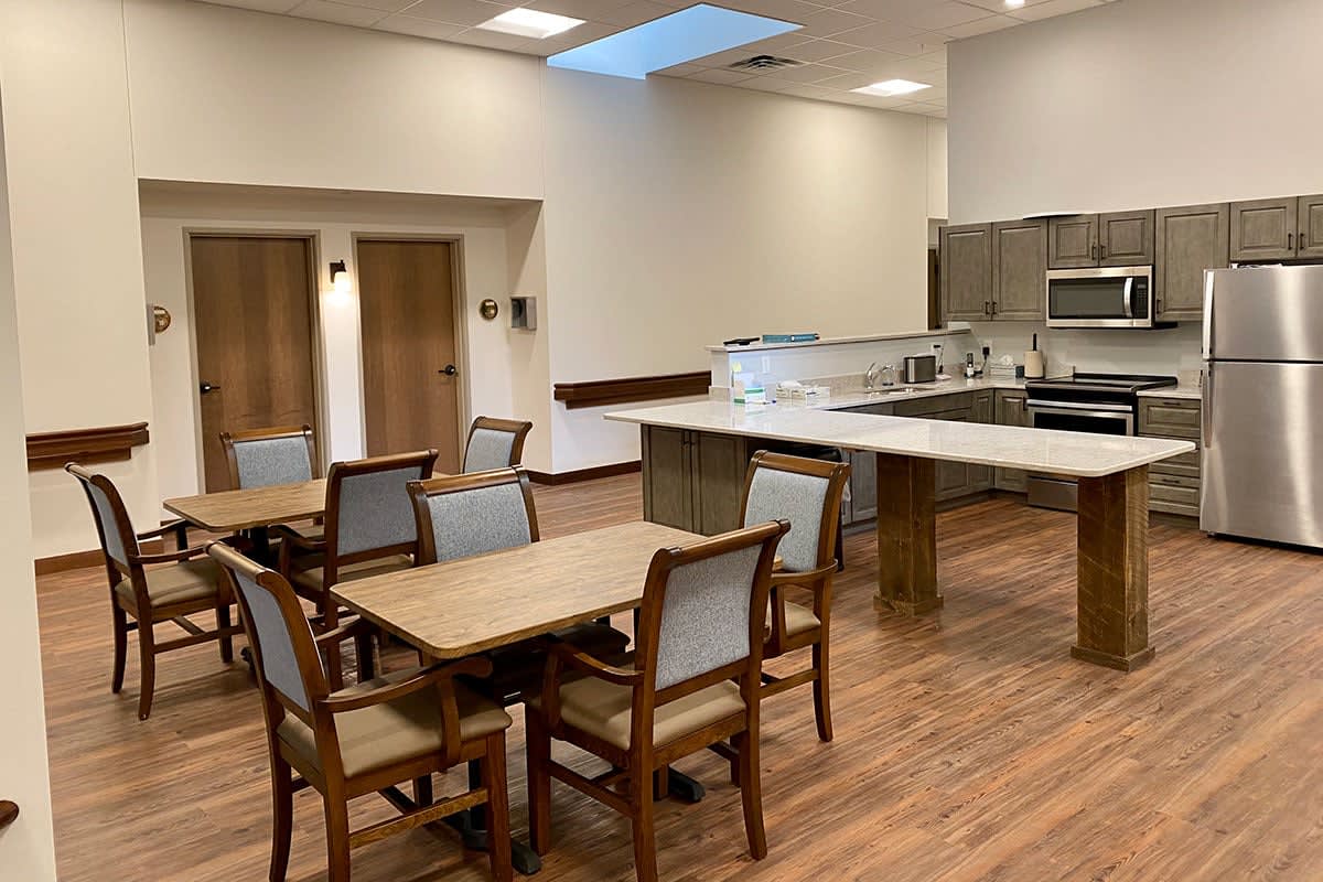A modern kitchen and dining area with wooden tables and chairs on a wood floor.