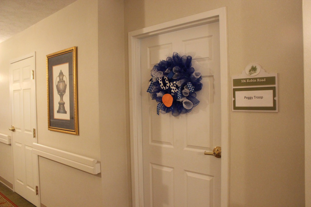 A decorated door in a hallway with a blue wreath and artwork on the wall.