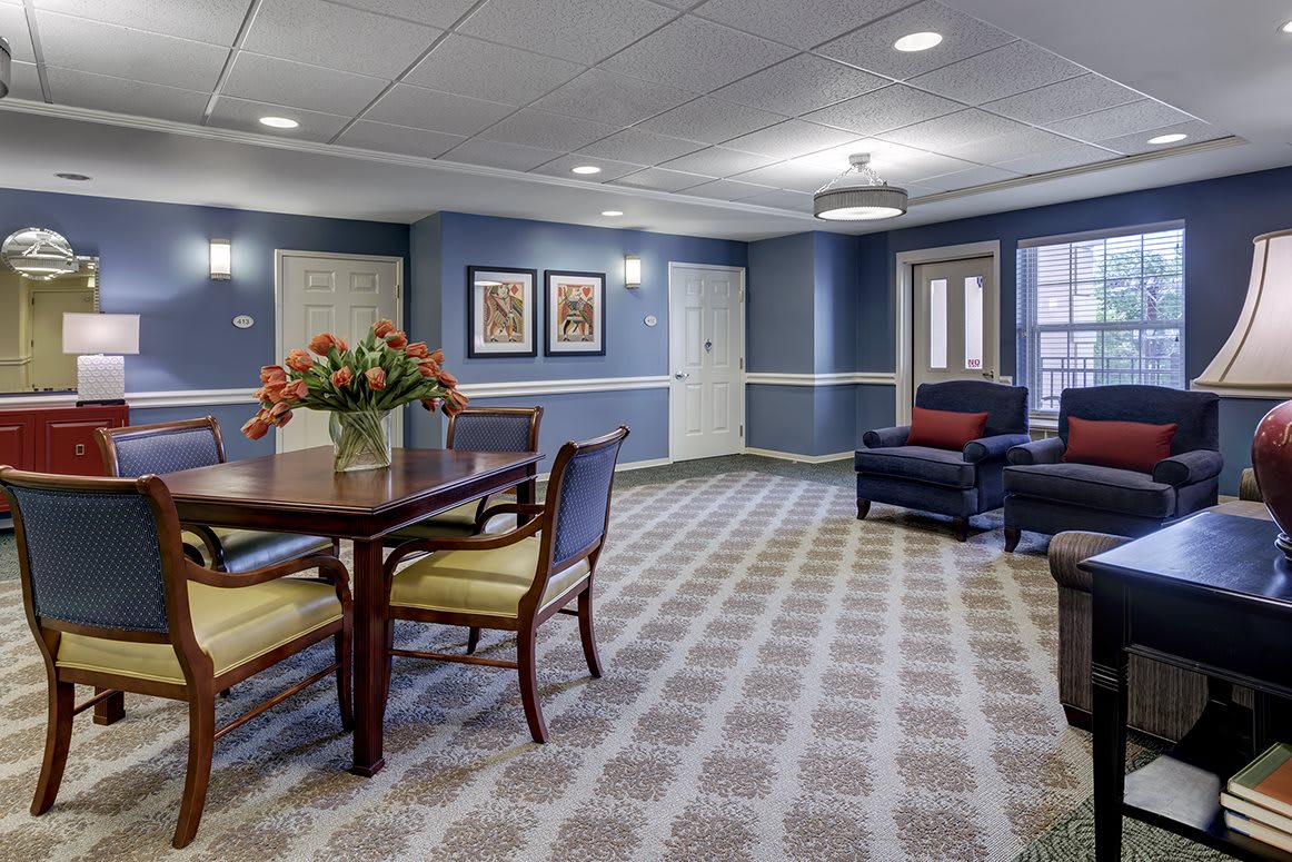 A cozy living room with blue walls, featuring a table with chairs and comfortable seating.