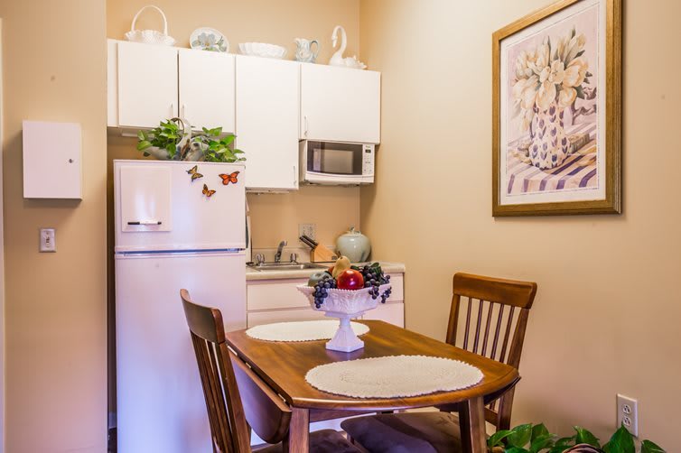 A cozy kitchen with a dining table set for two, featuring a refrigerator and microwave.