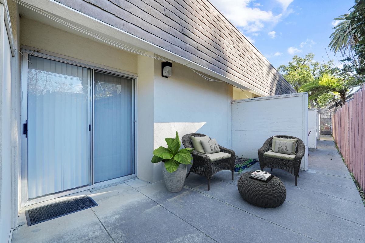 A modern patio with cozy outdoor seating and a potted plant.