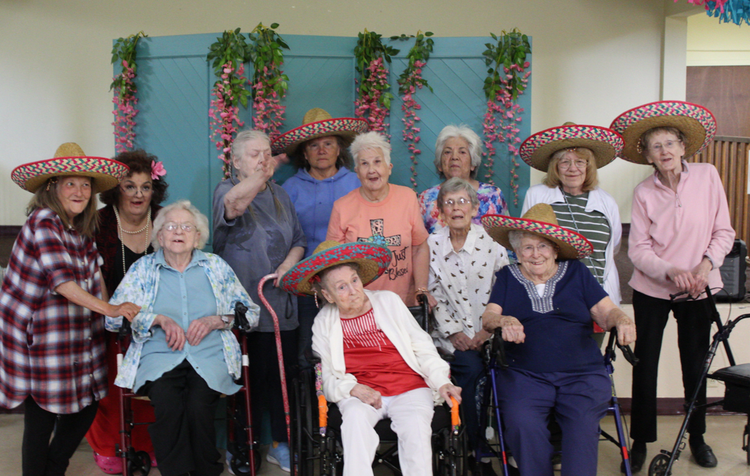 A joyful group of elderly individuals celebrating indoors with sombrero hats.
