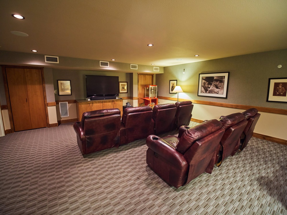 A cozy home theater room with plush seating and a large screen television.