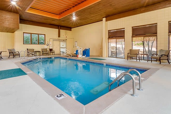 An inviting indoor swimming pool area with lounge chairs and a wooden ceiling, perfect for relaxation.