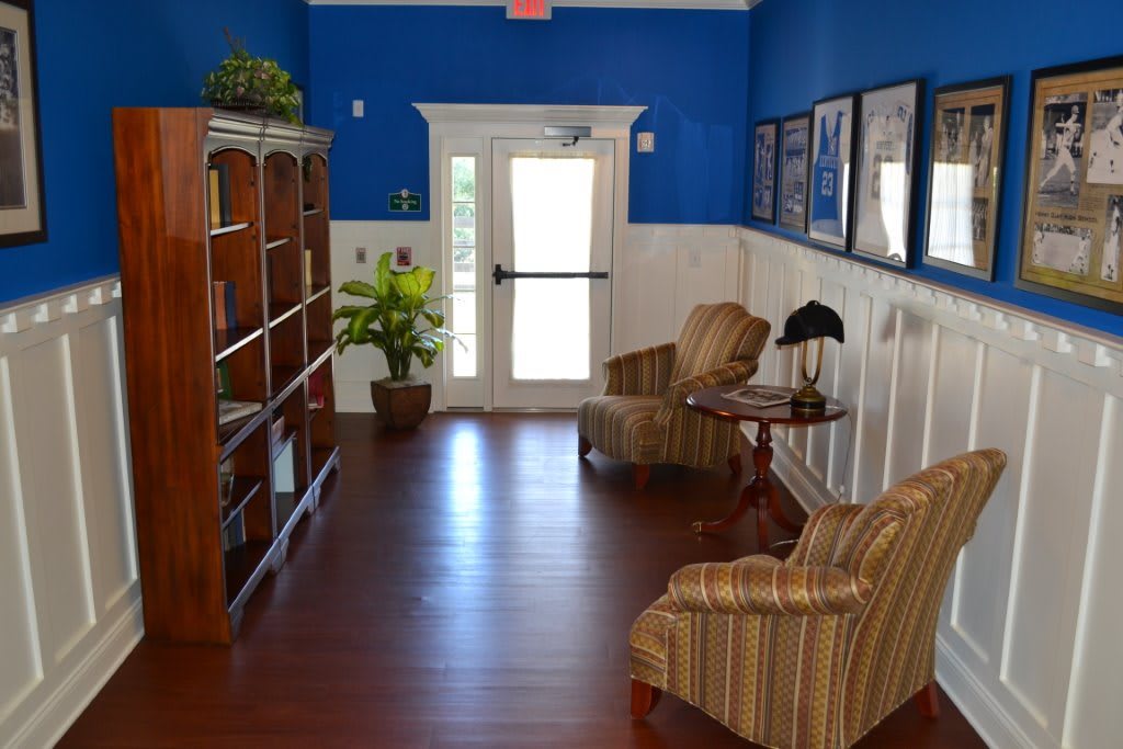 Cozy reading nook with bookshelves, armchairs, and decor in a brightly lit room.
