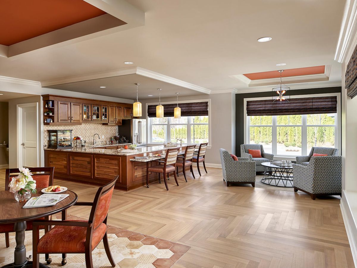 A modern open-concept kitchen and living room area with stylish furniture and wood flooring.