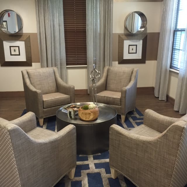 A cozy sitting area with four upholstered chairs around a round table, featuring modern decor and neutral tones.