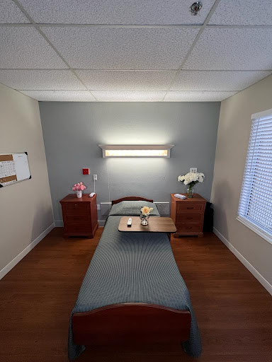 A cozy hospital room featuring a bed, bedside tables, and soft lighting.