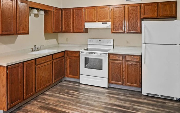 A modern kitchen featuring wood cabinets and white appliances, including a stove and refrigerator.