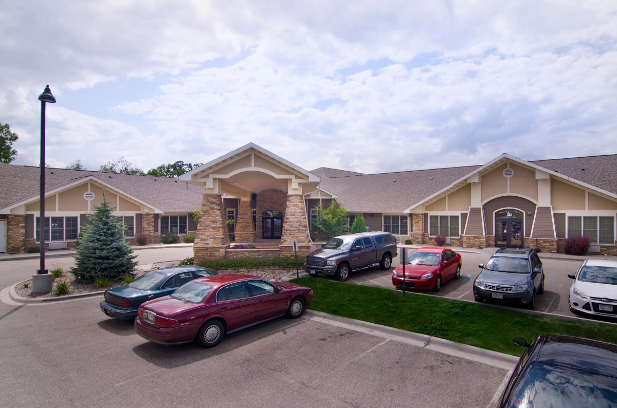 A suburban building with a parking lot filled with cars under a cloudy sky.