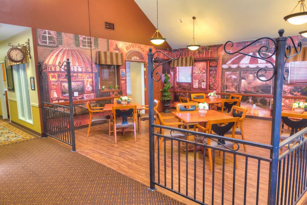 A cozy restaurant interior with dining tables and chairs, decorated with artistic wall murals.