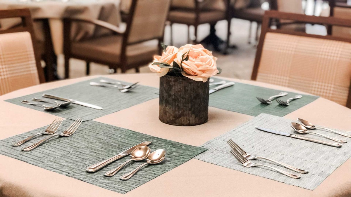 A beautifully arranged dining table with flowers and neatly placed silverware.