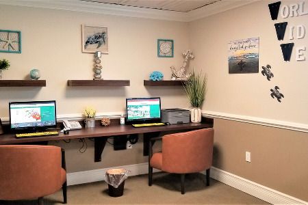A cozy office workspace with two computers, chairs, and decorative elements.