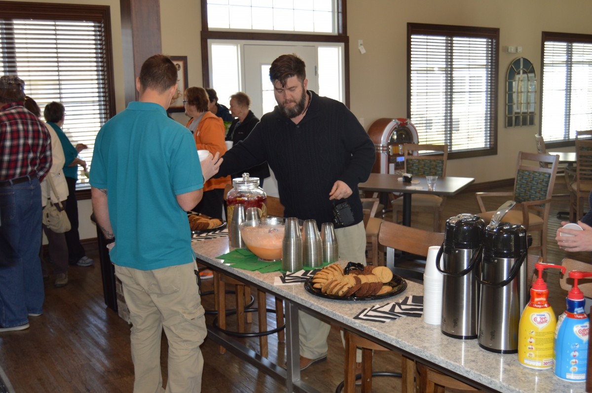People serving themselves at a buffet table during an indoor event.