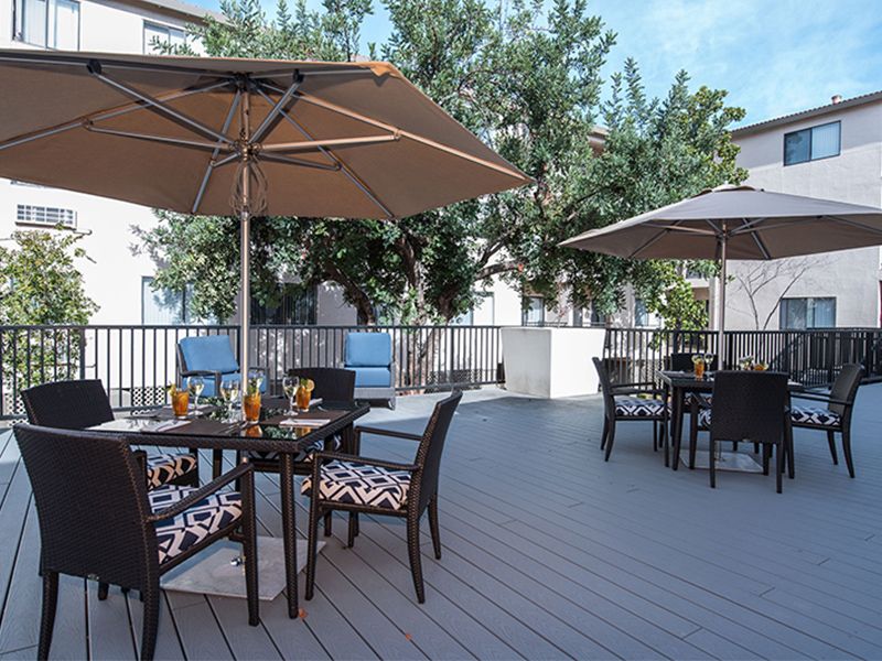 A peaceful outdoor patio area with tables, chairs, and umbrellas.