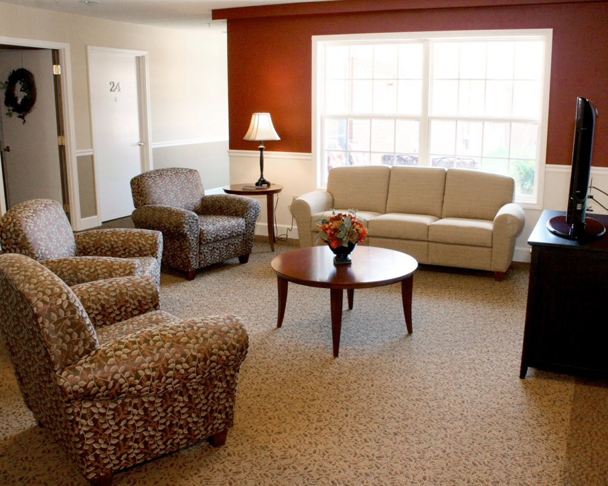 A cozy living room with comfortable seating, including a sofa and chairs, centered around a wooden coffee table.